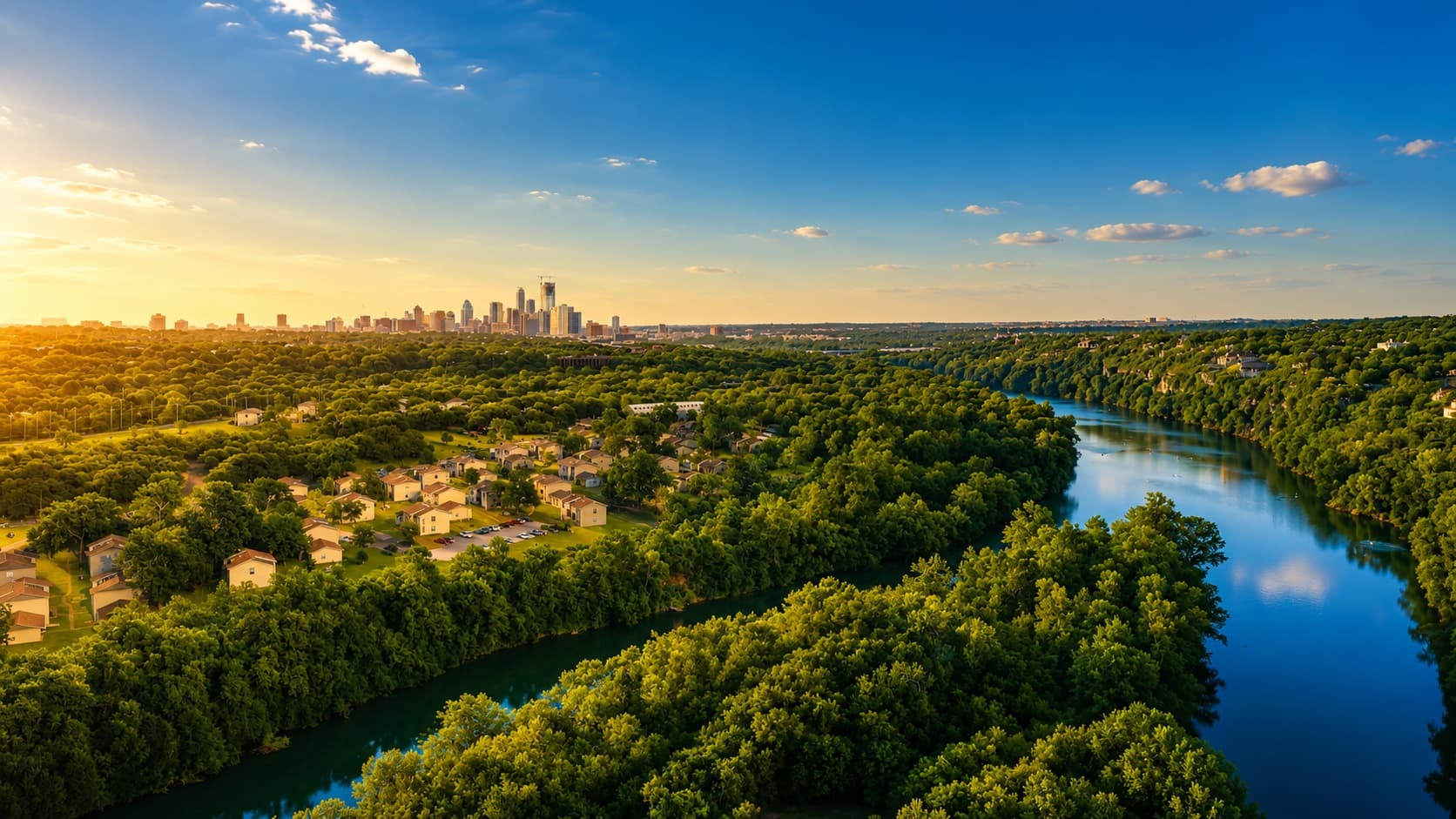Aerial view of the Austin skyline beyond the wooded greenbelt and the Colorado River at golden hour